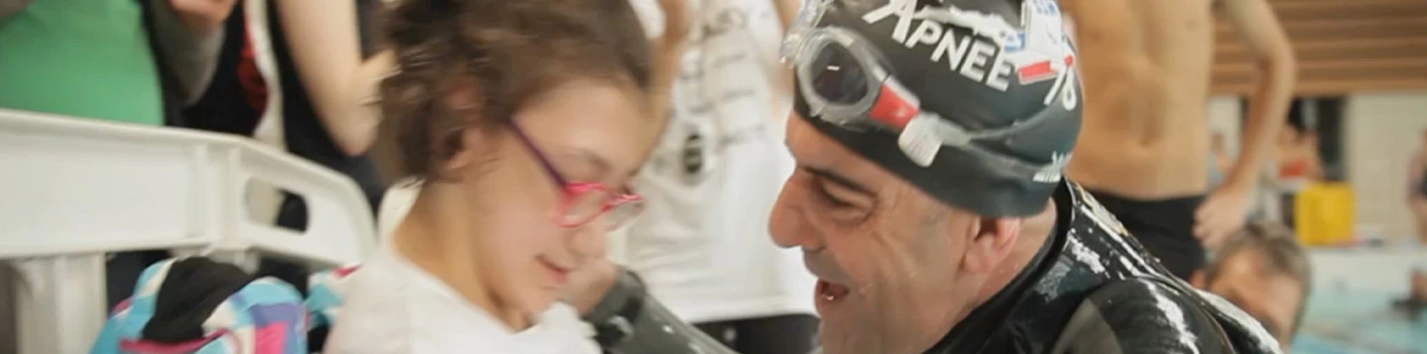 Andy Cabrera Ávila, con gorro de natación "Apnée 78", sonríe junto a una niña con gafas tras finalizar un récord solidario de apnea.