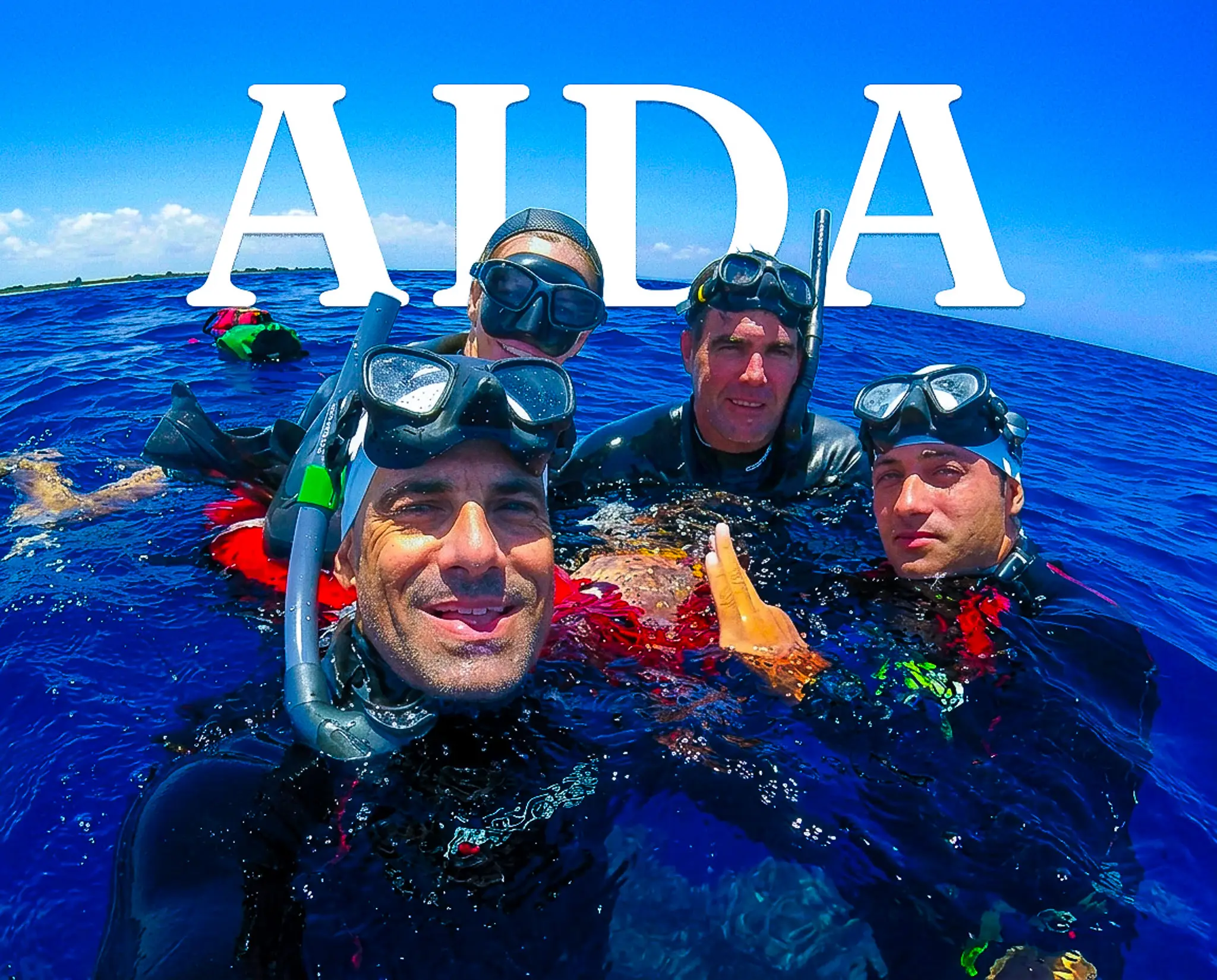 Cuatro apneístas sonríen en una selfie en aguas abiertas, con el logo de AIDA superpuesto, tras una sesión de entrenamiento en el mar.